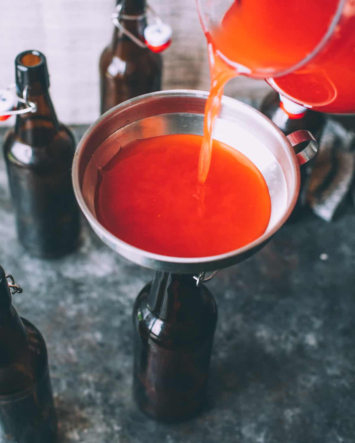 pouring fermented soda into flip top bottles with a funnel