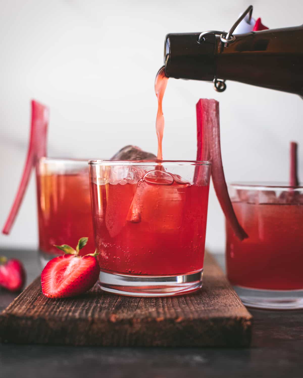 pouring a bottle of strawberry rhubarb soda into a glass