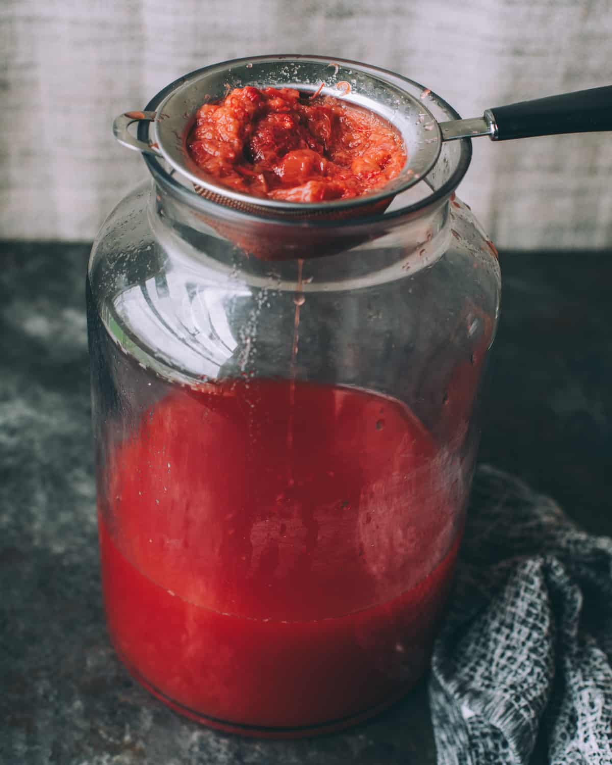 straining the strawberries and rhubarb out of the soda