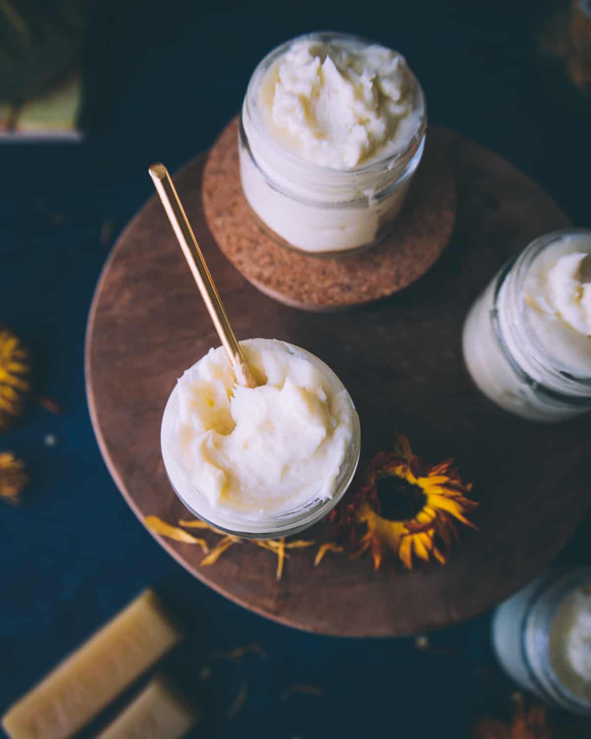 Small jars of calendula cream on a wooden table. 