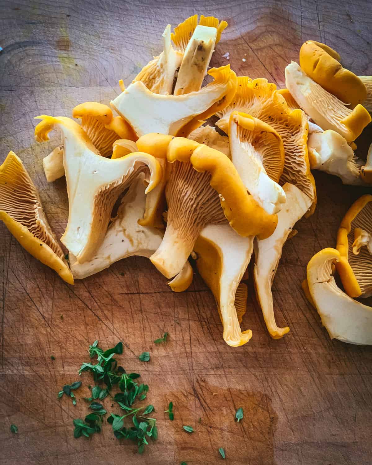 cut chanterelles on a cutting board with fresh thyme