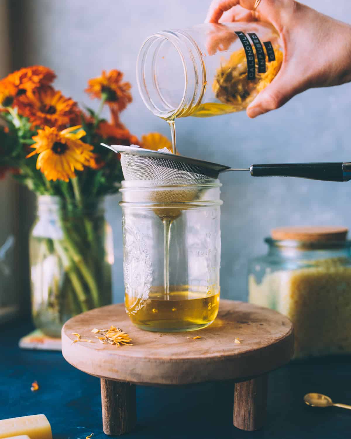 Infused calendula oil pouring into a mesh strainer with cheesecloth into a new jar. 