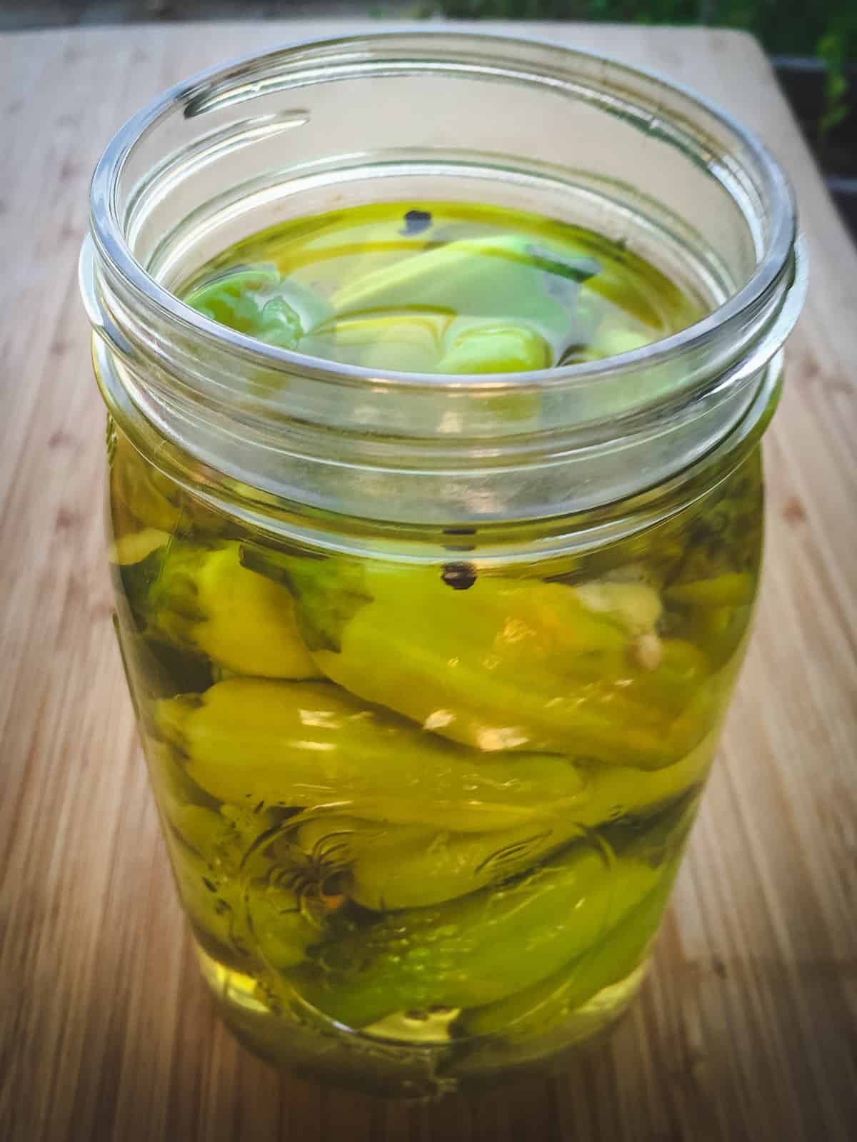 A quart mason jar of pickled pepperoncini peppers