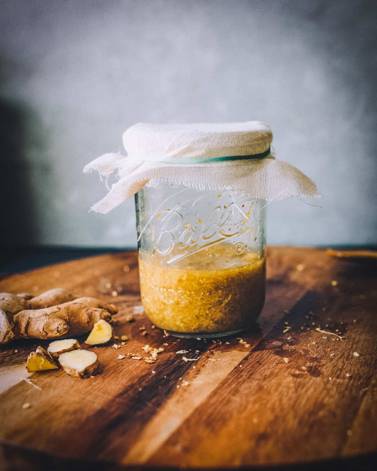 a jar of fermenting ginger bug starter covered with a cheesecloth