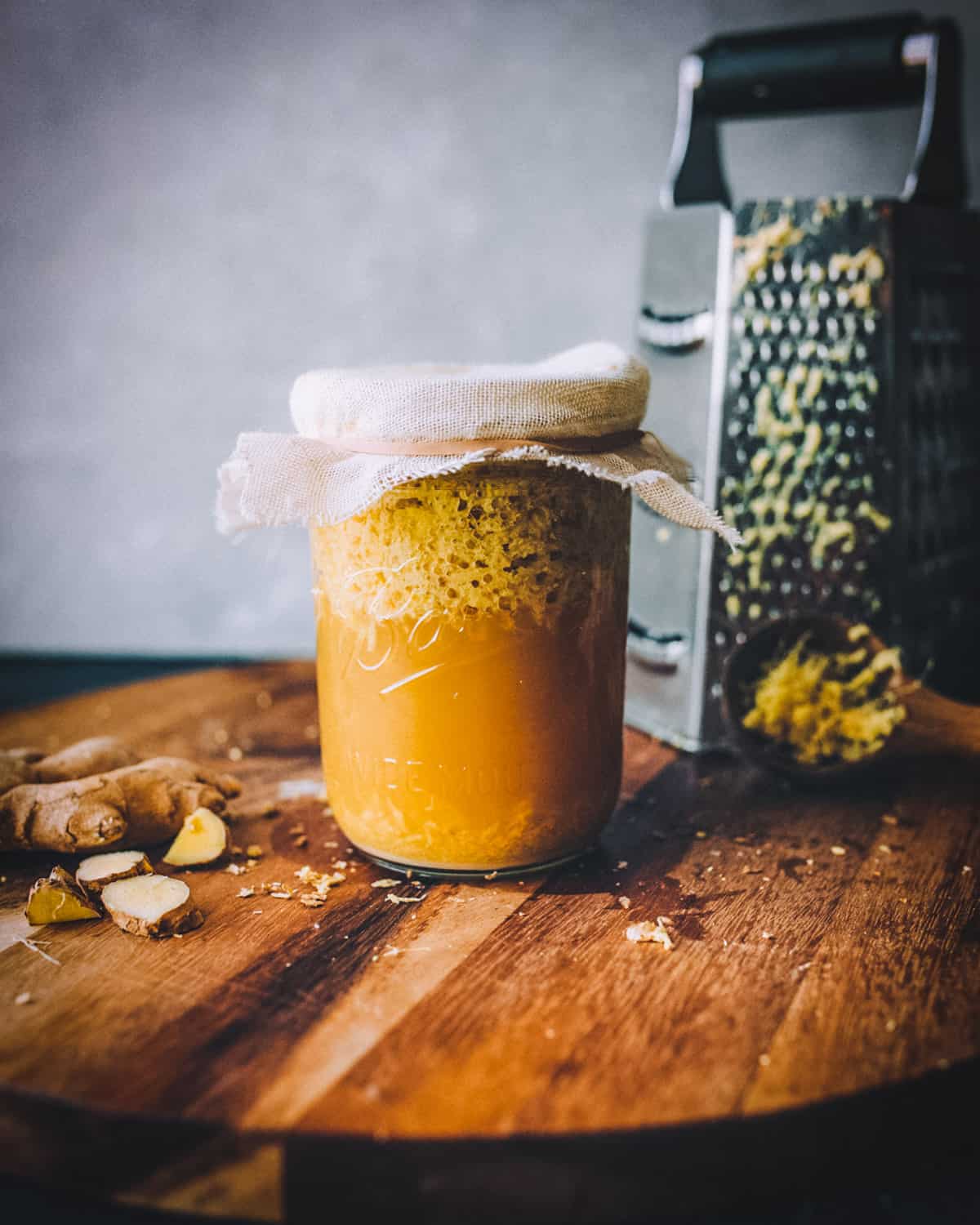 a jar full of bubbling ginger bug that is covered with cheesecloth