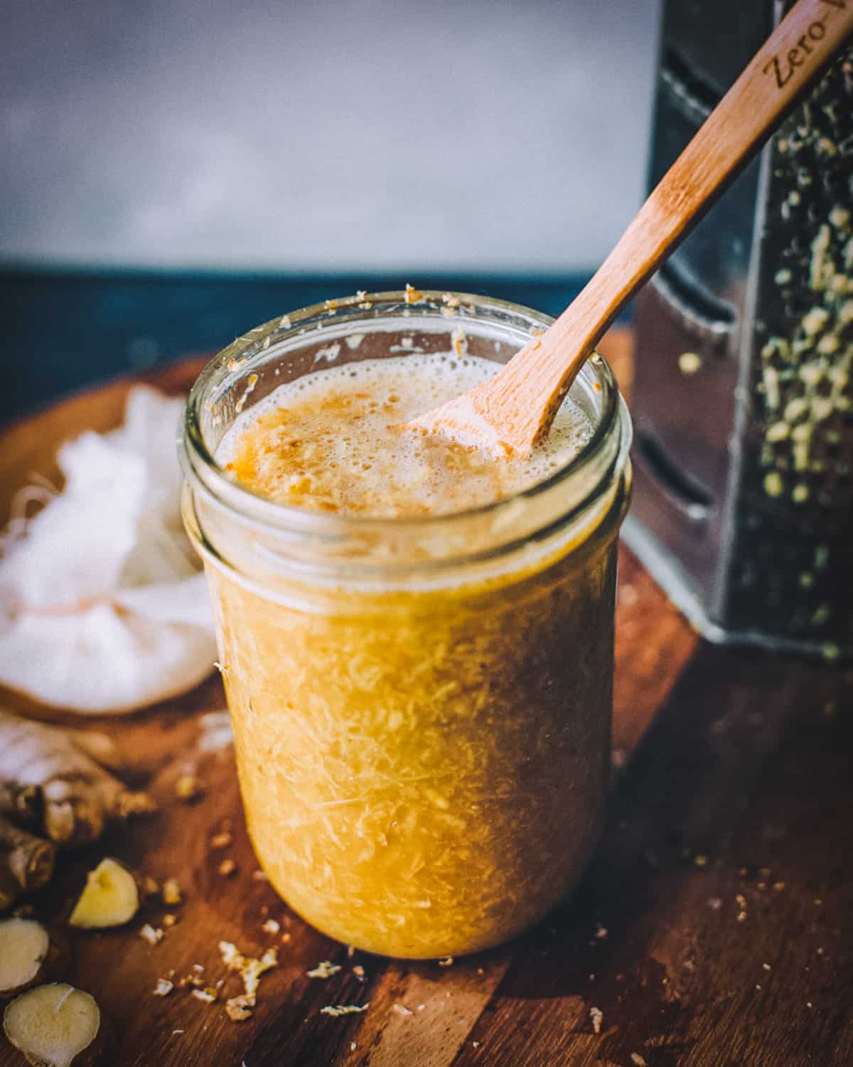 a pint jar of bubbling ginger bug with a wooden spoon
