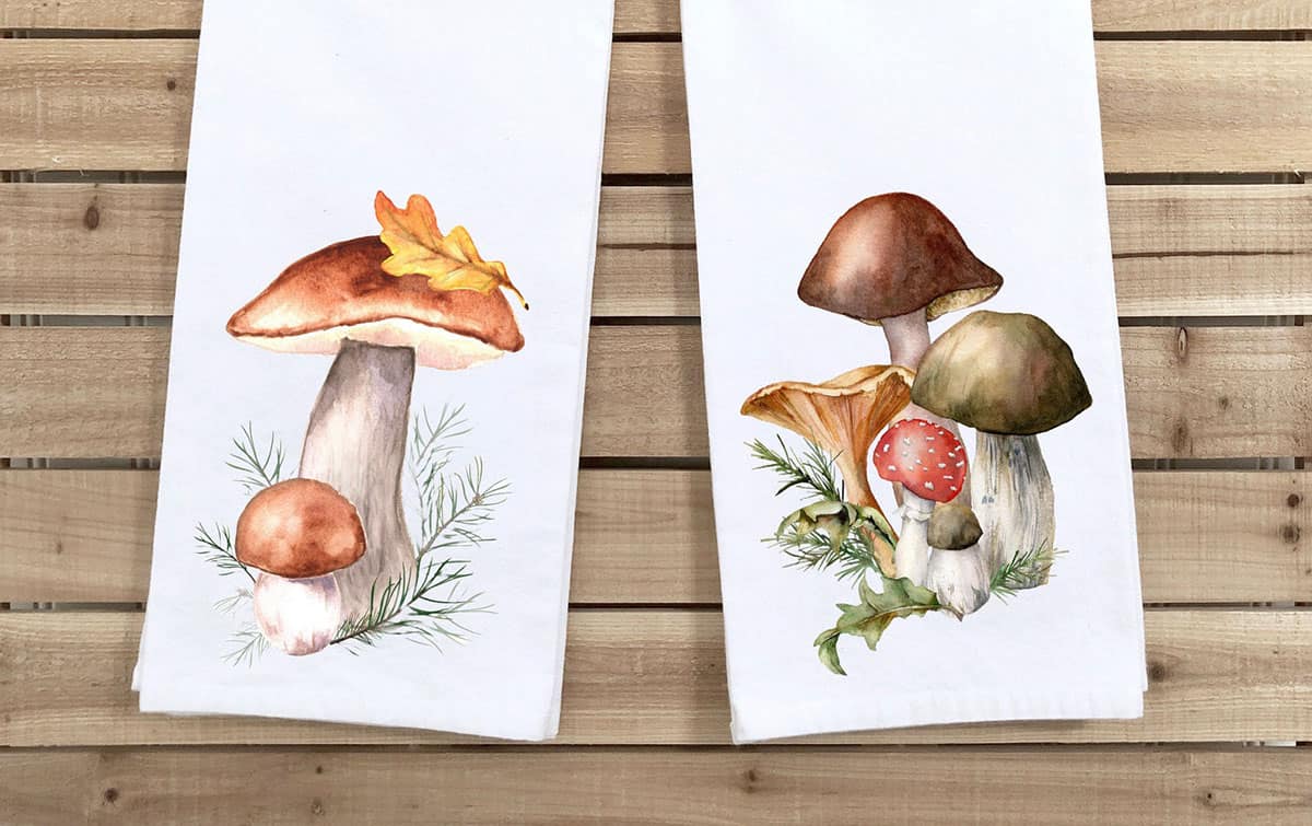 two tea towels with woodland mushrooms prints on a wooden background