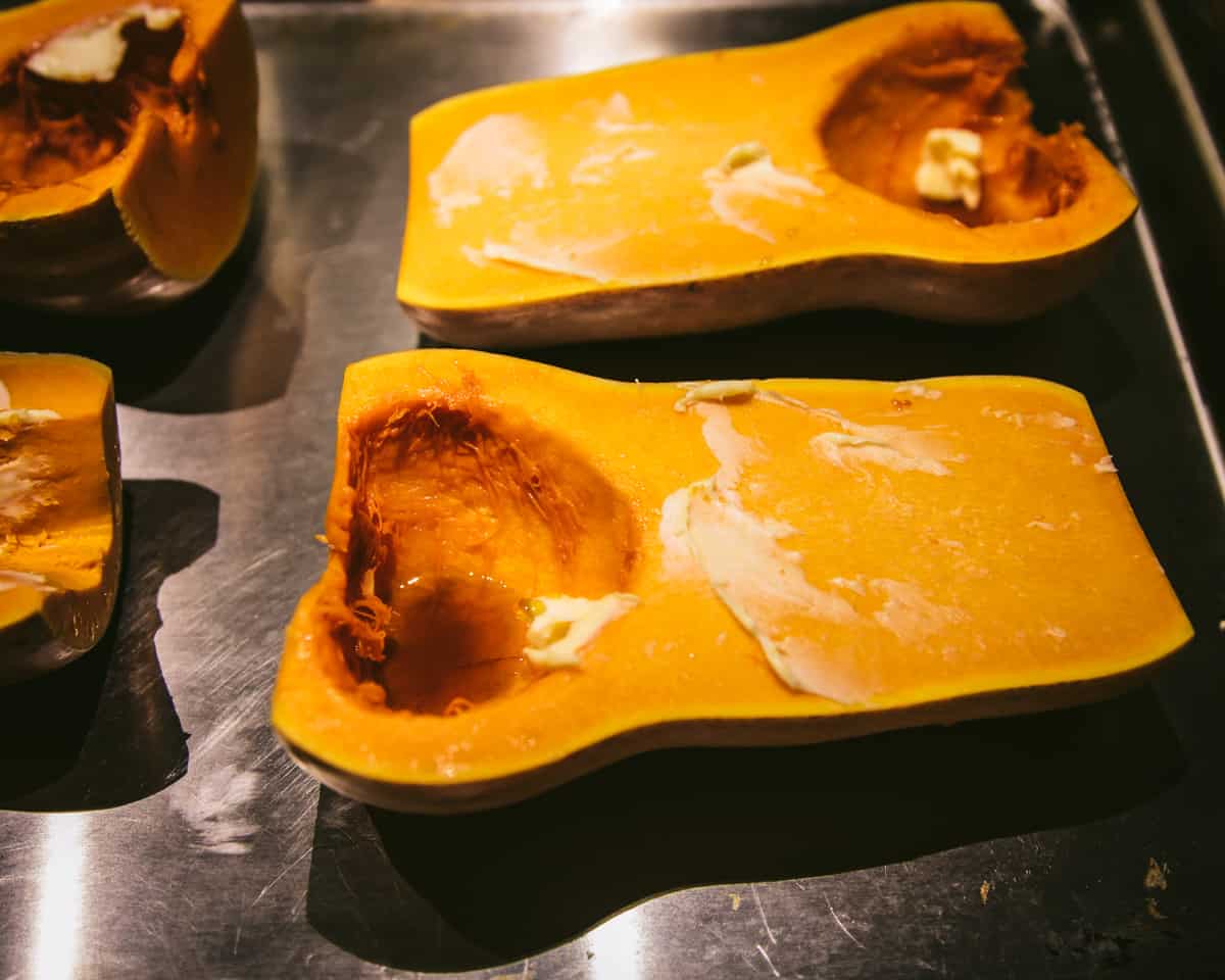 butternut squash on a baking sheet with butter and maple syrup