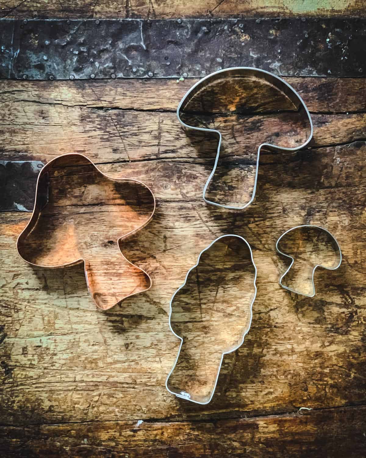 four different mushroom cookie cutters on a wooden table