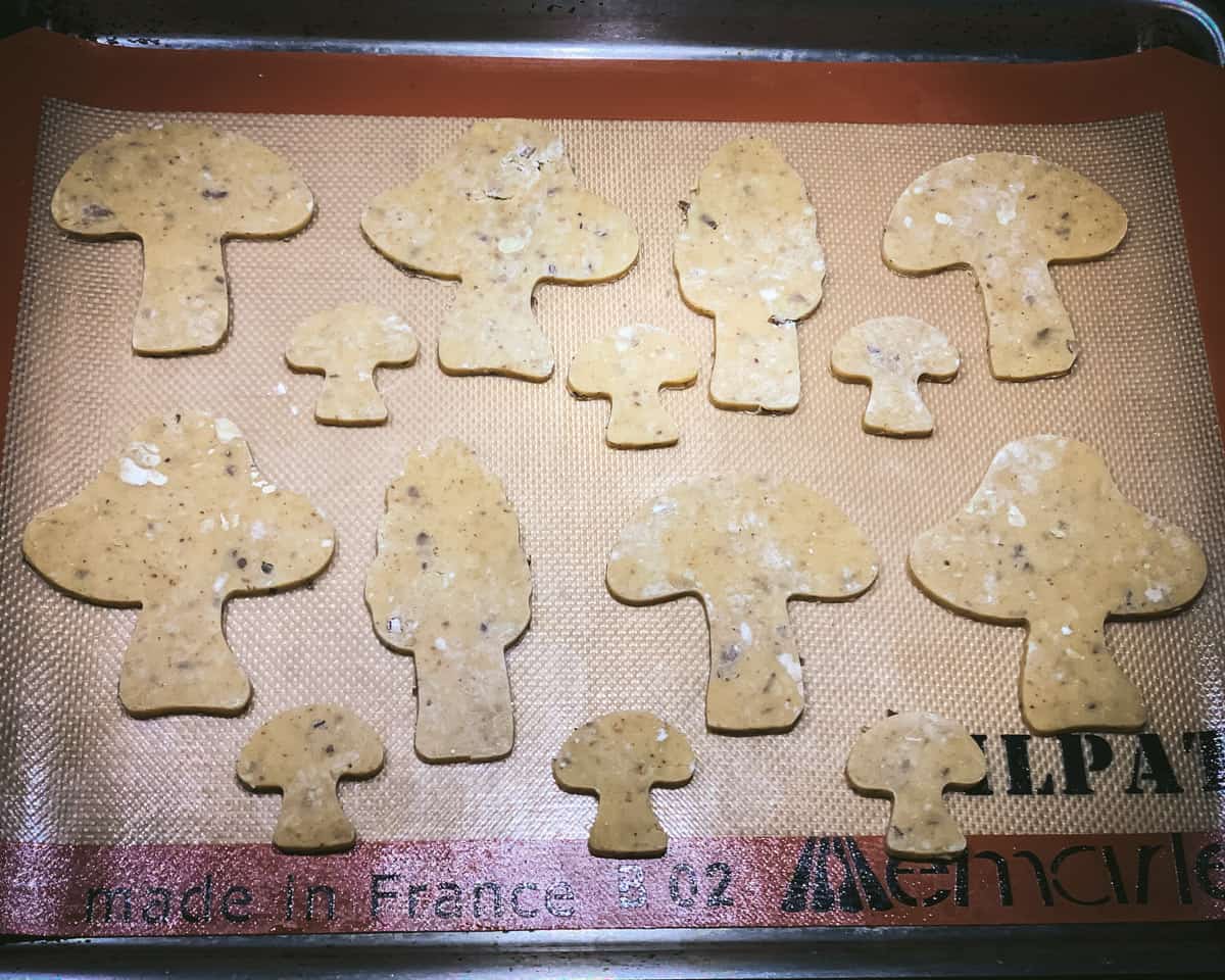 unbaked mushroom cookies on a sheet pan with a silicone mat