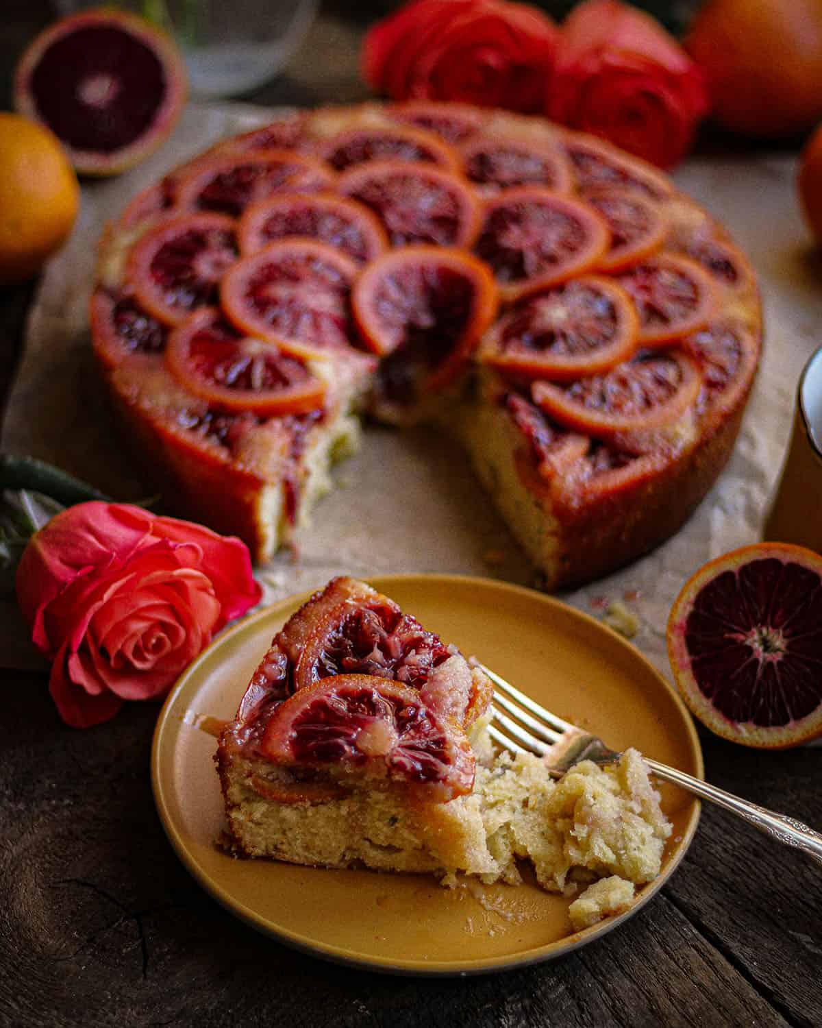 Finished blood orange upside down cake, with the oranges facing up and a slice cut out onto a plate. 