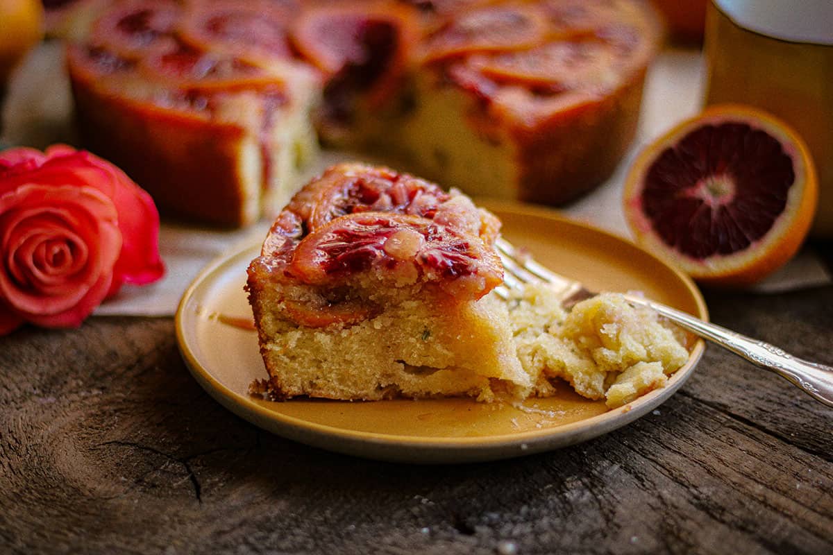 Slice of blood orange upside down cake being eaten on a plate.