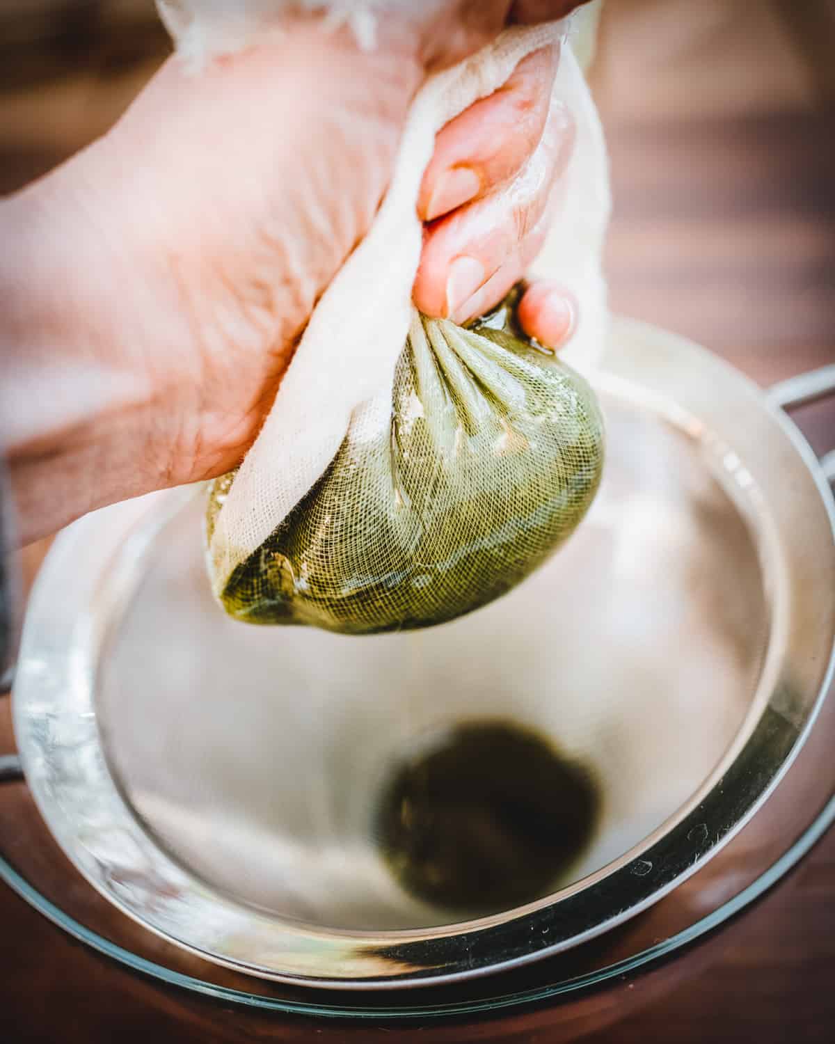 Chickweed and oil in muslin cloth being squeezed. 