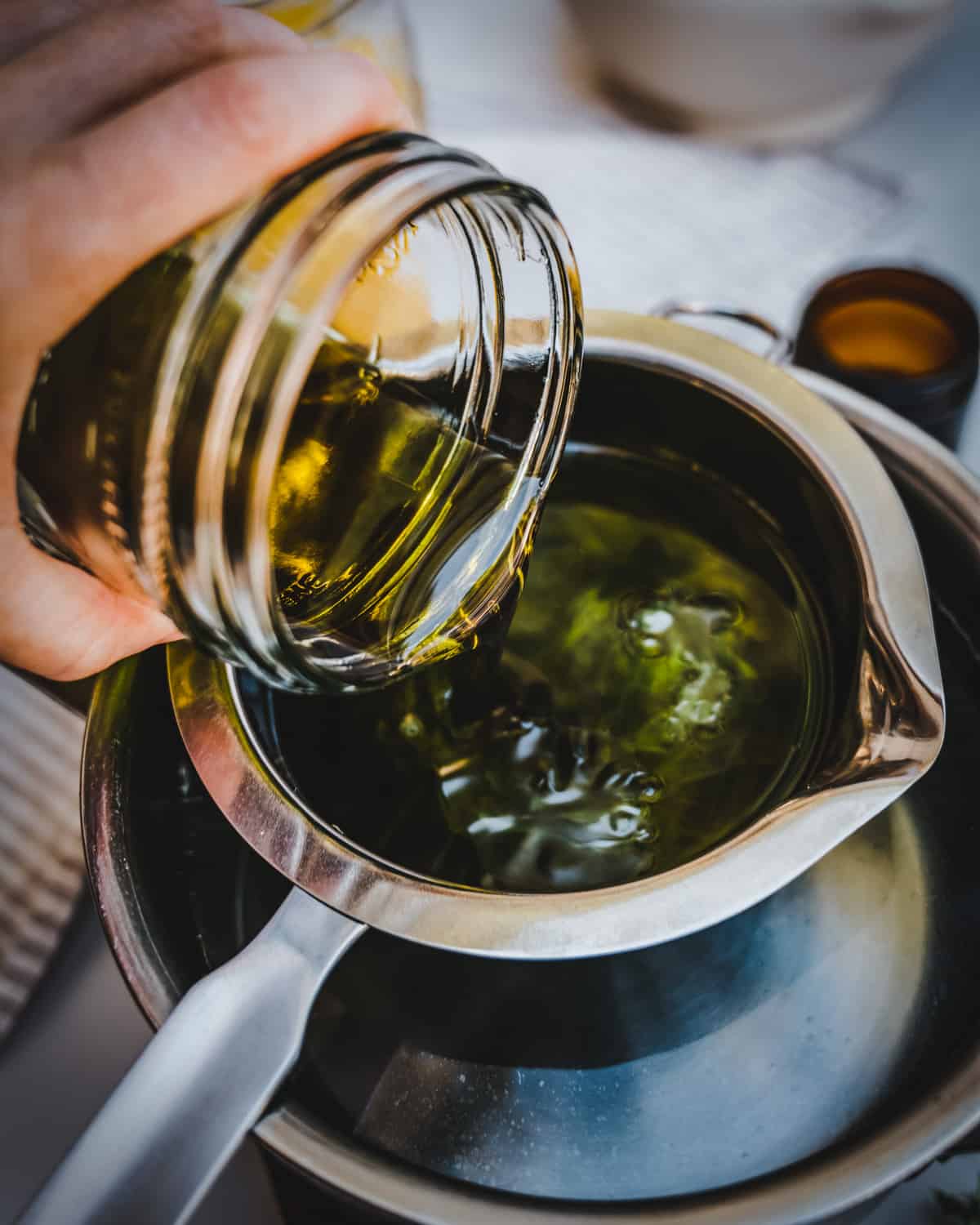Chickweed oil being poured into a double boiler to make salve