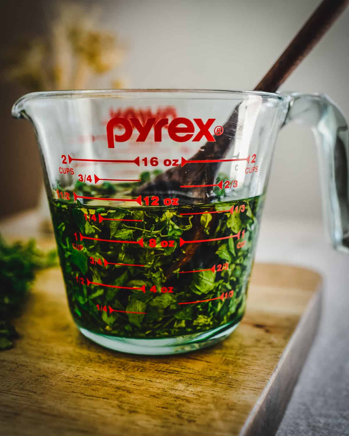 Chickweed in oil being stirred in a pyrex pouring glass. 