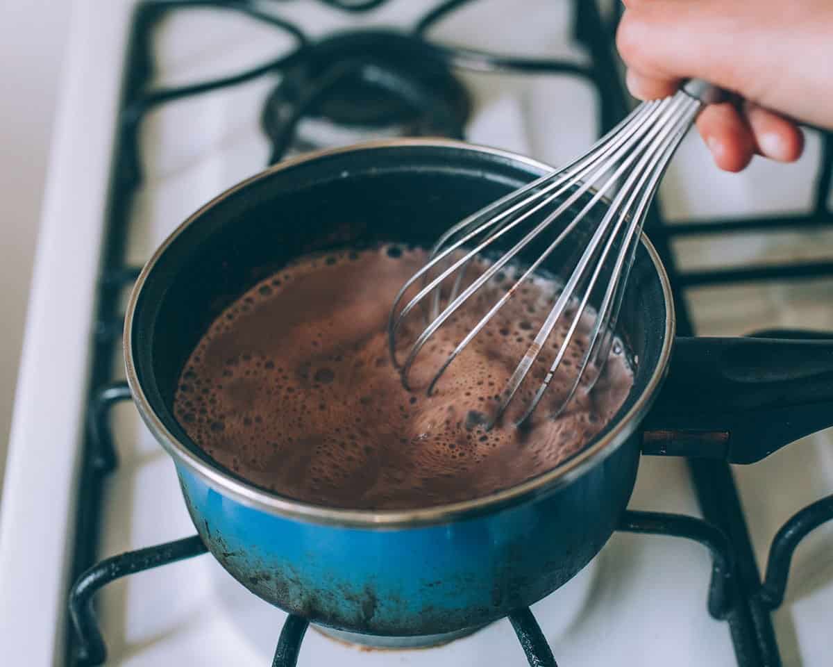 whisking the mushroom hot cocoa in a pot on the stove top