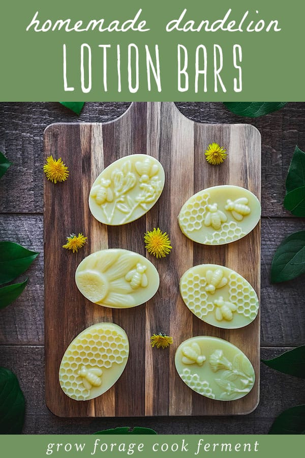 Dandelion lotion bars made with a honeycomb, bee, and flower mold, on a wooden cutting board with fresh dandelions surrounding. Green block on the top with white lettering reads homemade dandelion lotion bars. 
