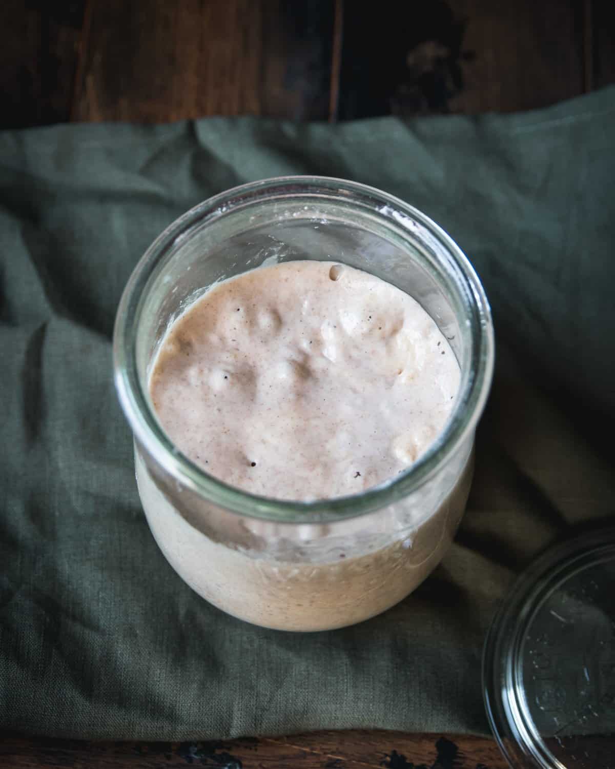 Top view of a bubbling sourdough starter on a green cloth. 