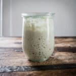 A jar of sourdough starter on a wood surface.