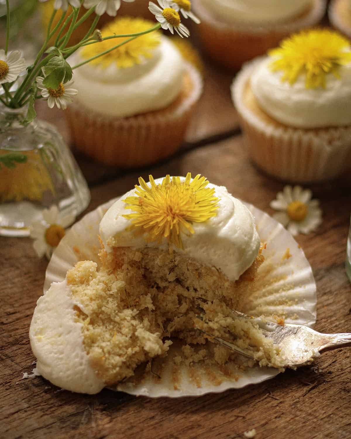 Dandelion cupcake with opened cupcake paper, half eaten. 