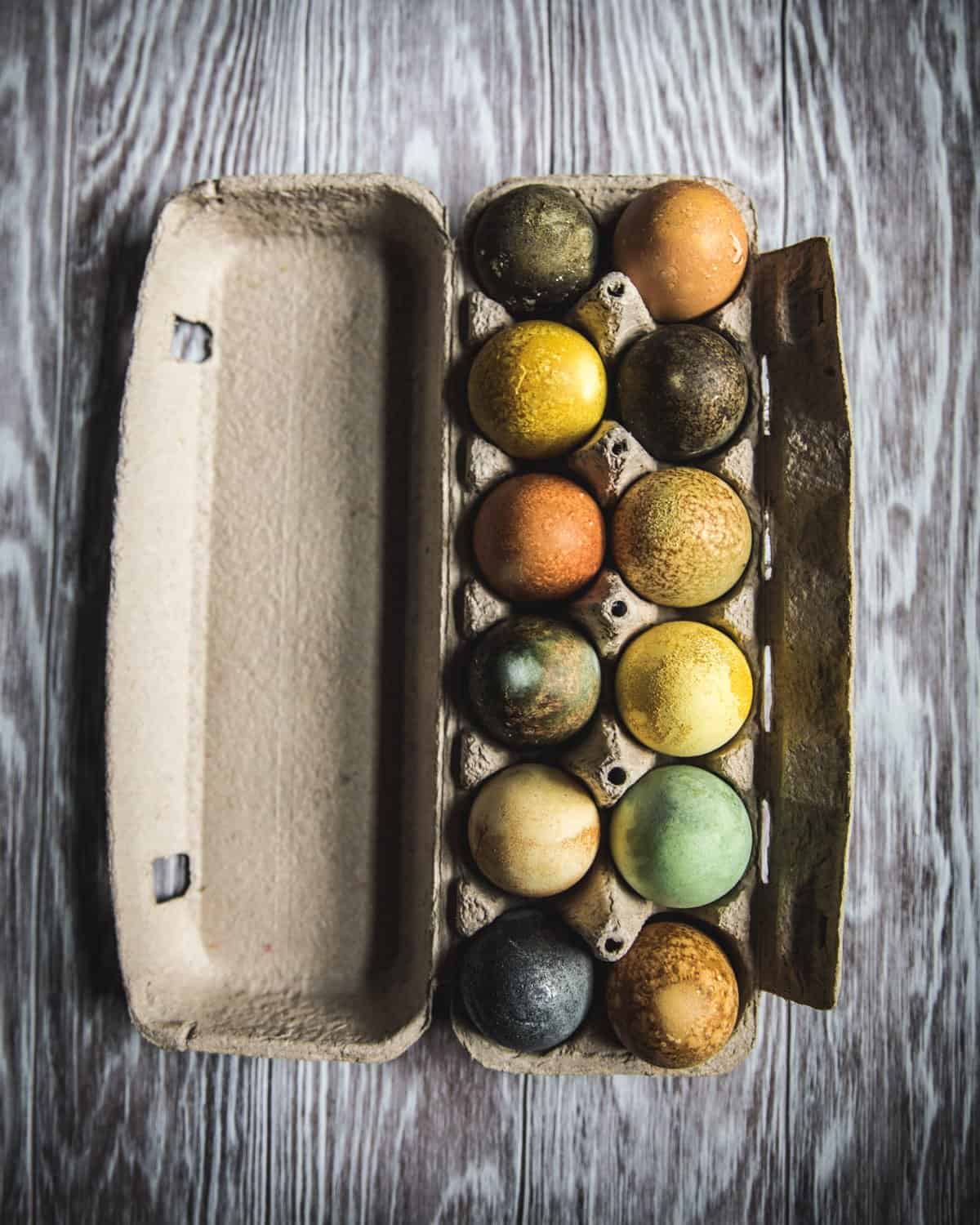 an egg carton of naturally dyed eggs showing the different colors