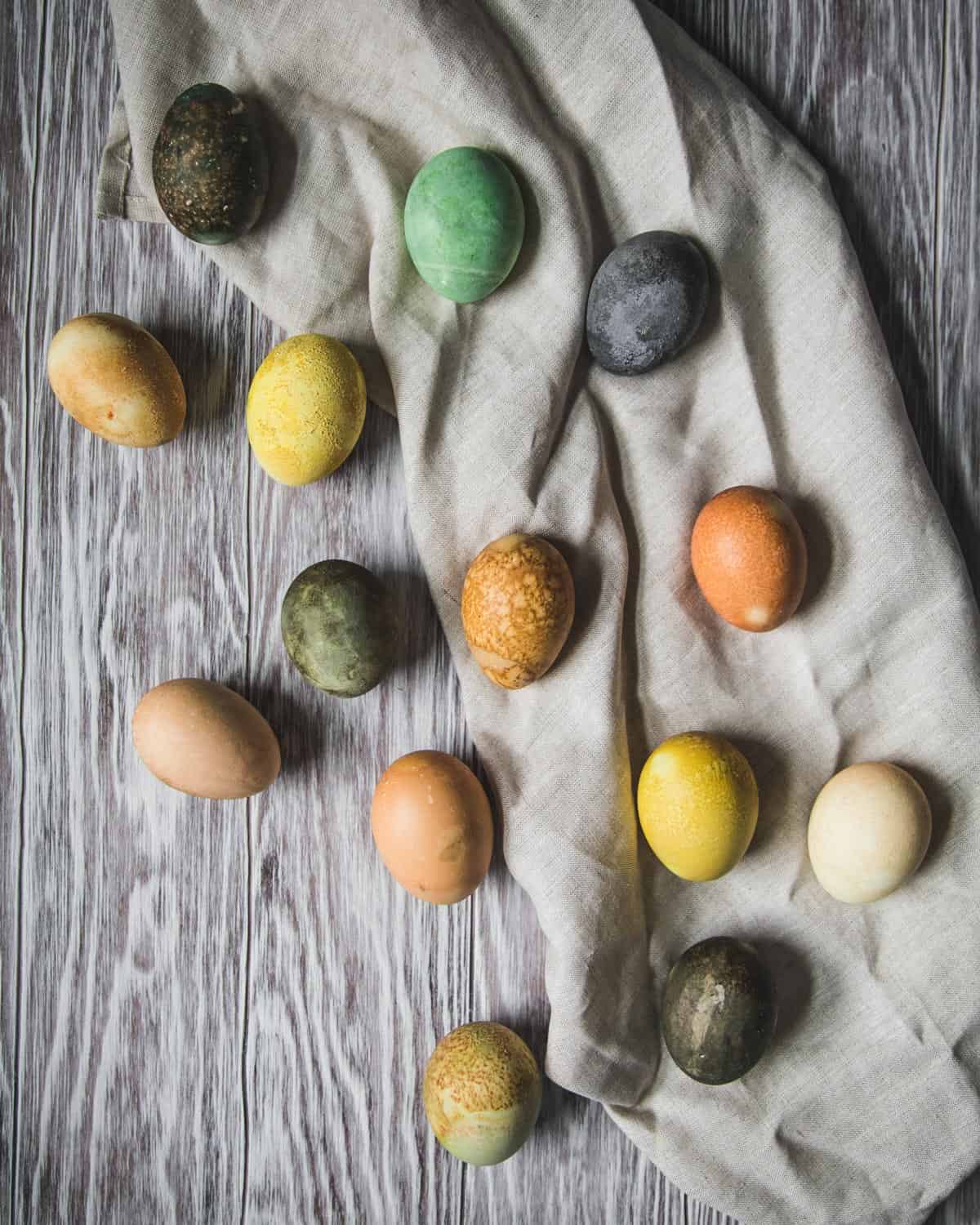 a white table with different colored eggs that have been dyed with herbal tea