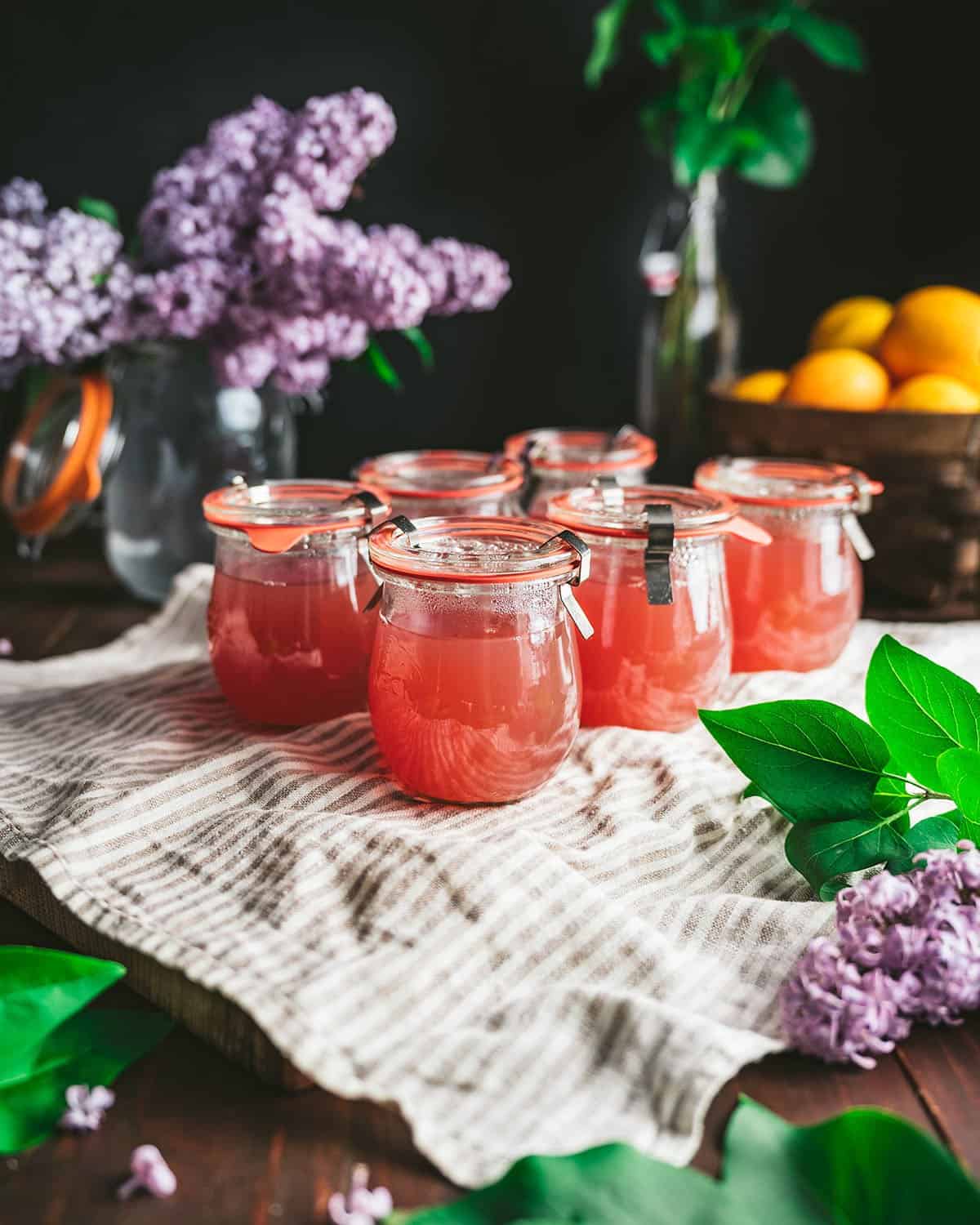 Six jars of sealed lilac jelly jars cooling on a towel. 