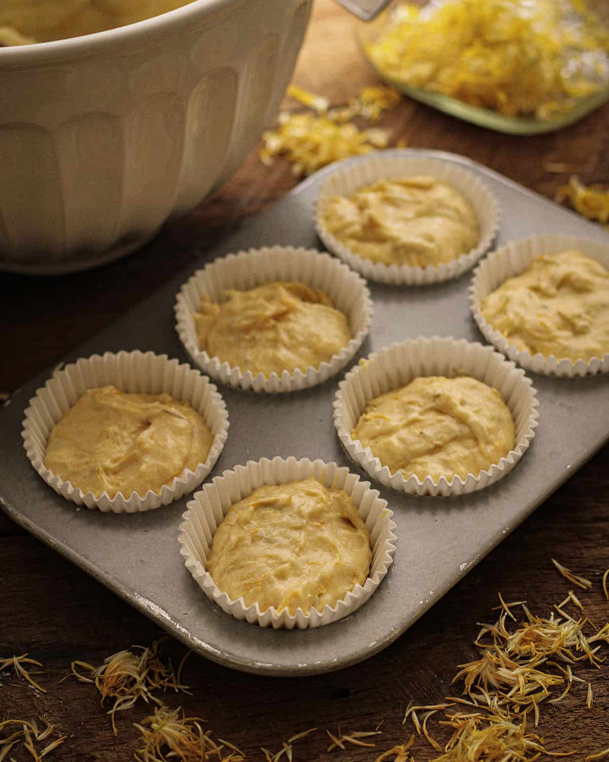 Muffin tin with liners filled with dandelion cupcake batter. 