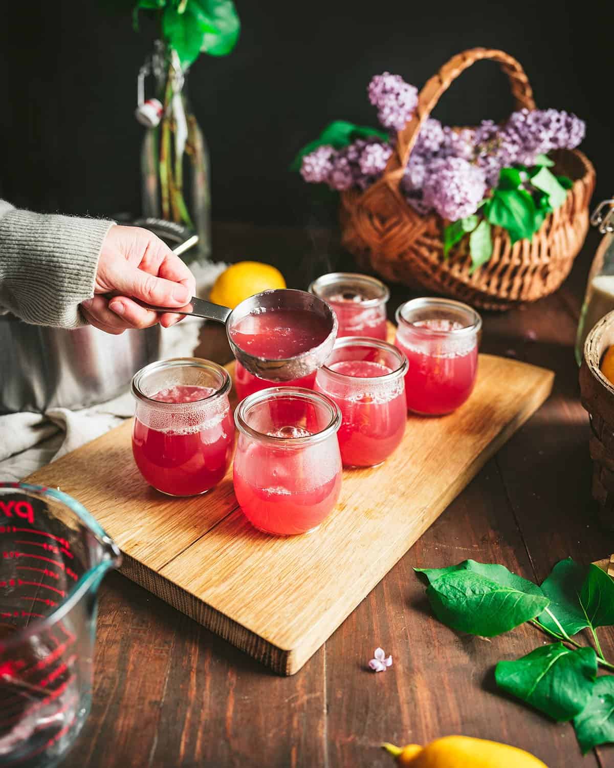 Six jars being filled with lilac jelly mixture