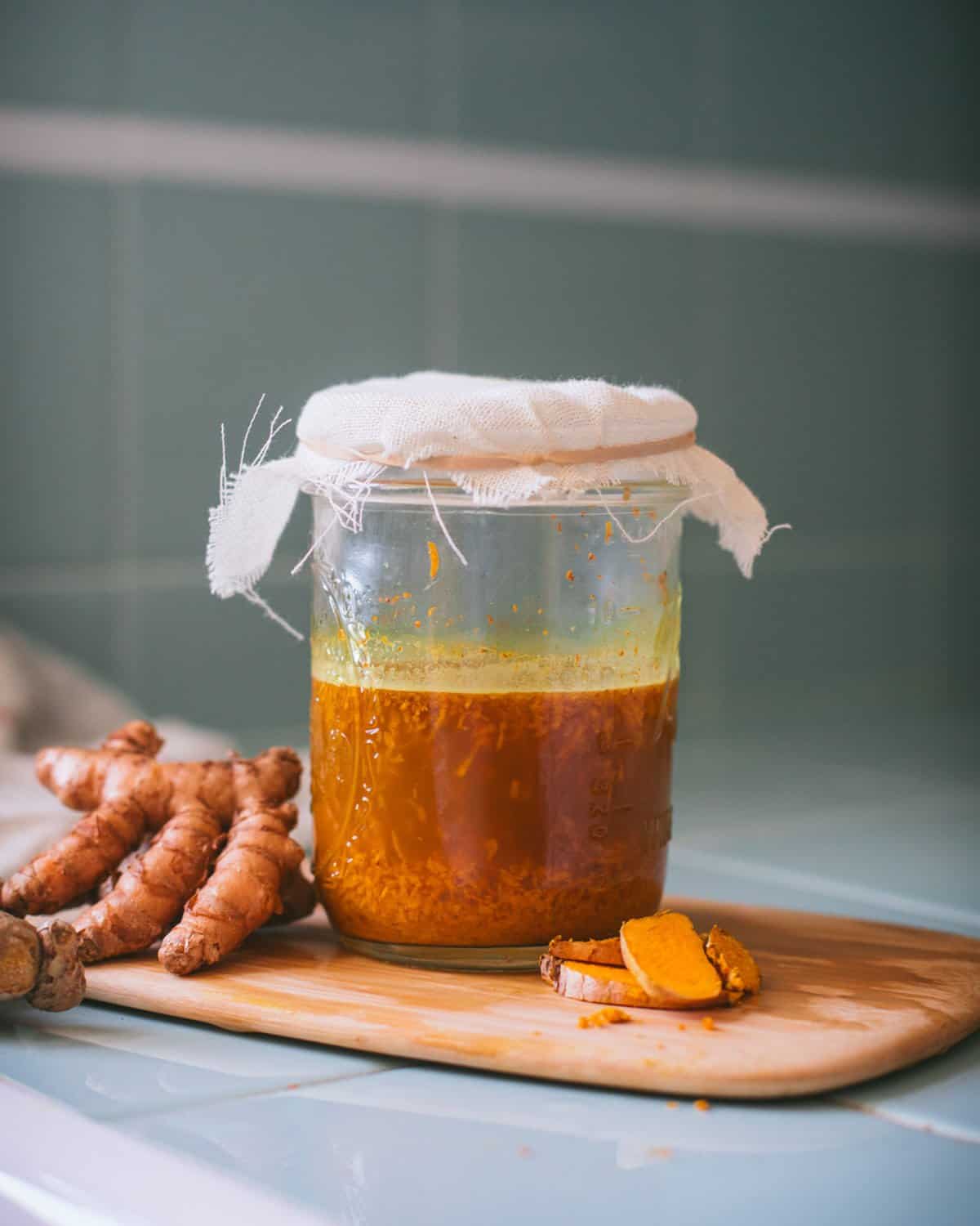 a jar of turmeric bug covered with a cheesecloth