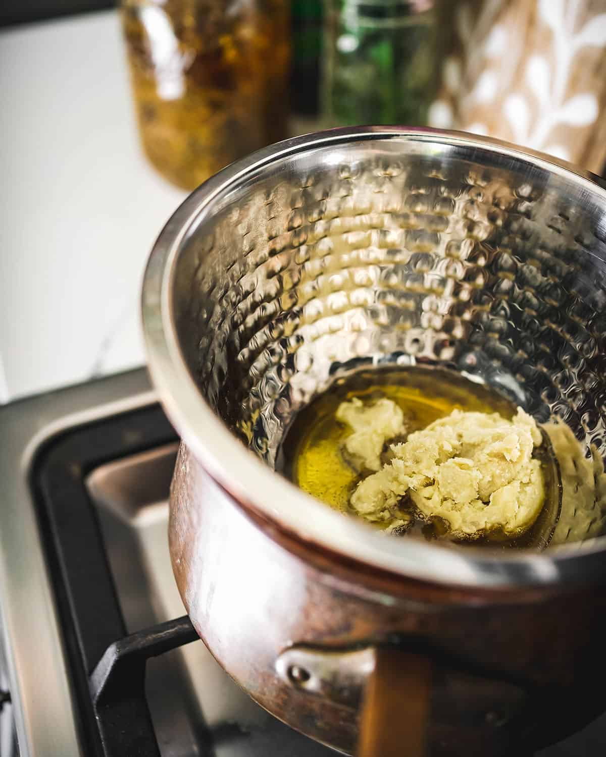 A self-created double boiler with a bowl over a pot, melting the oils and shea butter. 