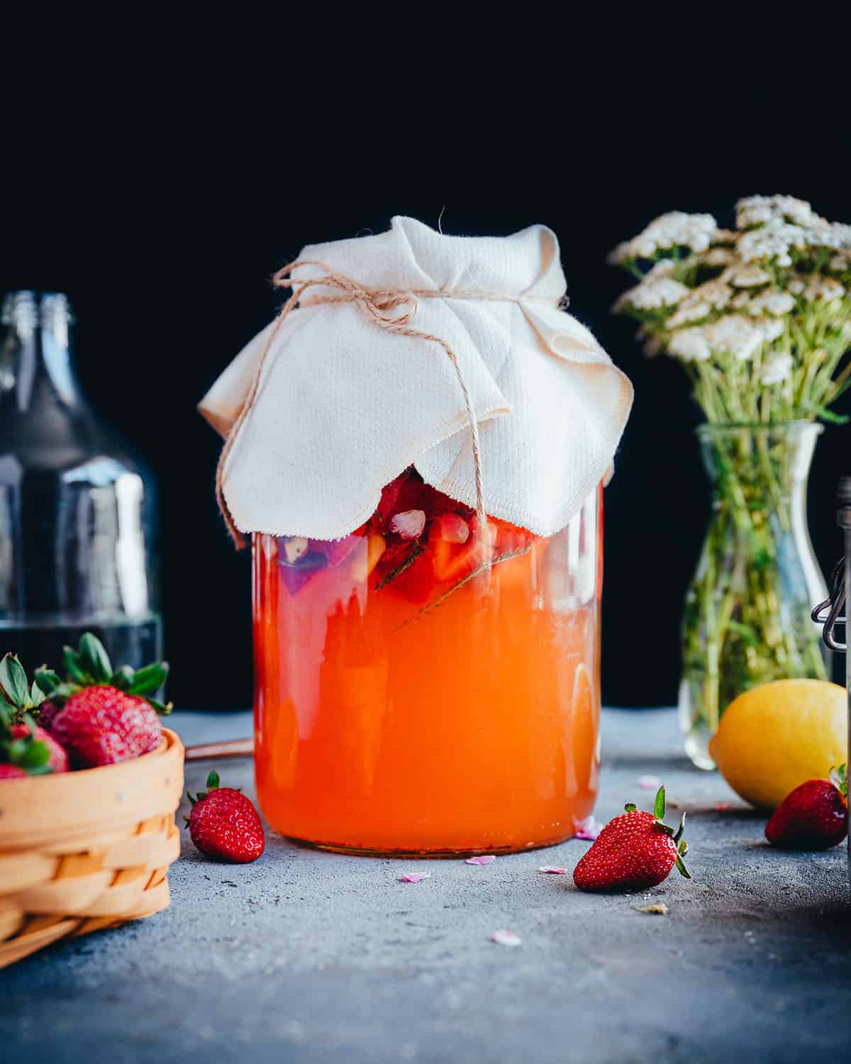 Large jar with homemade soda fermenting, covered with cheesecloth.