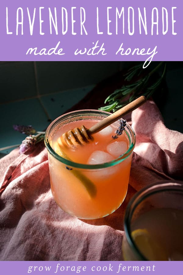 A cup of lavender lemonade with a honey stick stirring. 