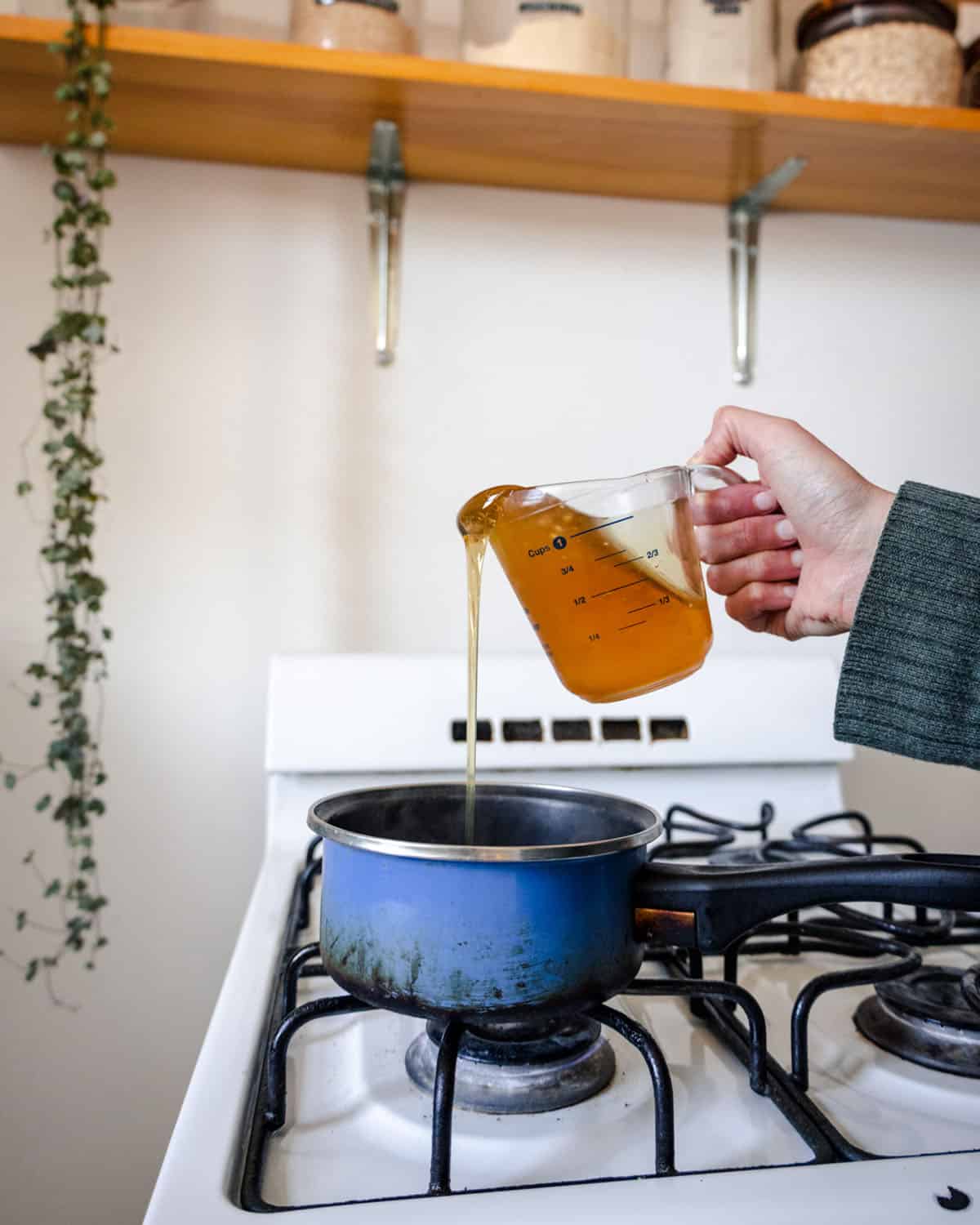 Honey being poured into a pot on the stove. 