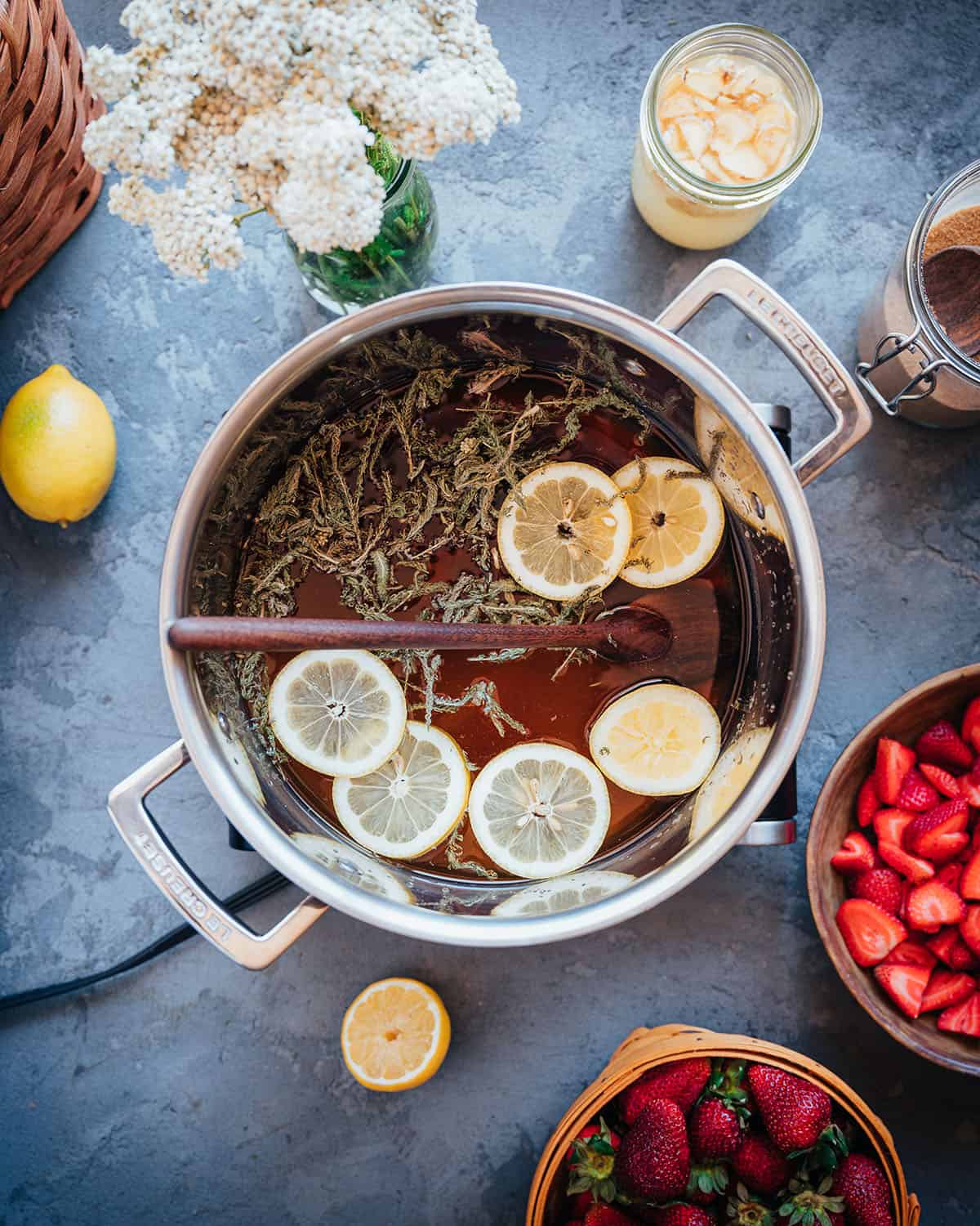 A large pot with the homemade soda base liquid, with sliced lemons floating on top.