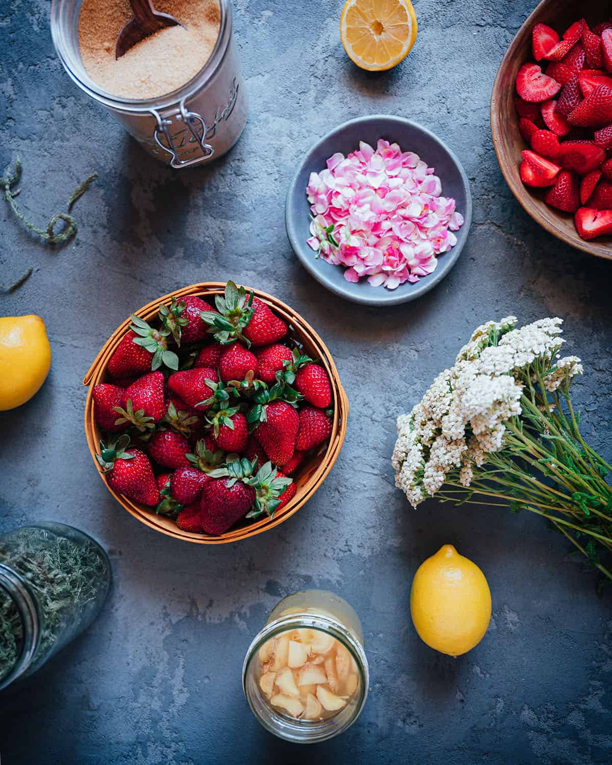 Ingredients for yarrow strawberry soda in bowls, with yarrow bunched.