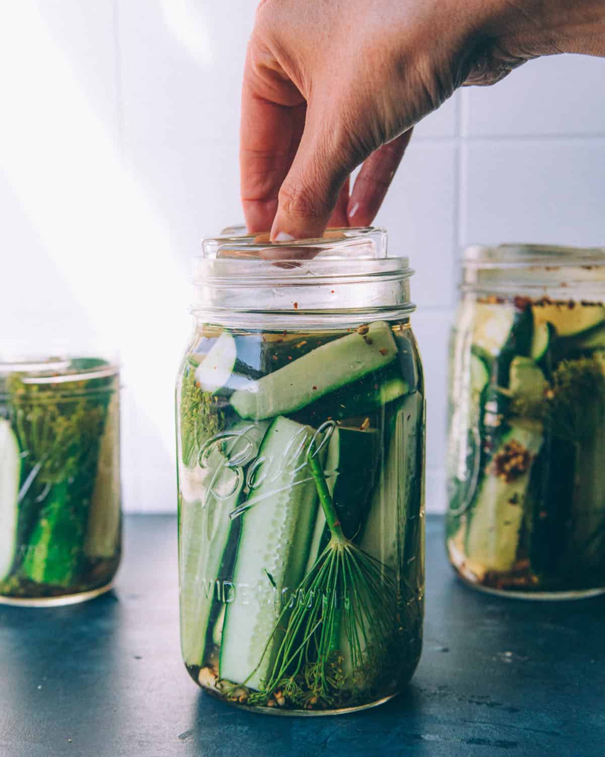 A fermentation weight being placed on top of the cucumbers. 