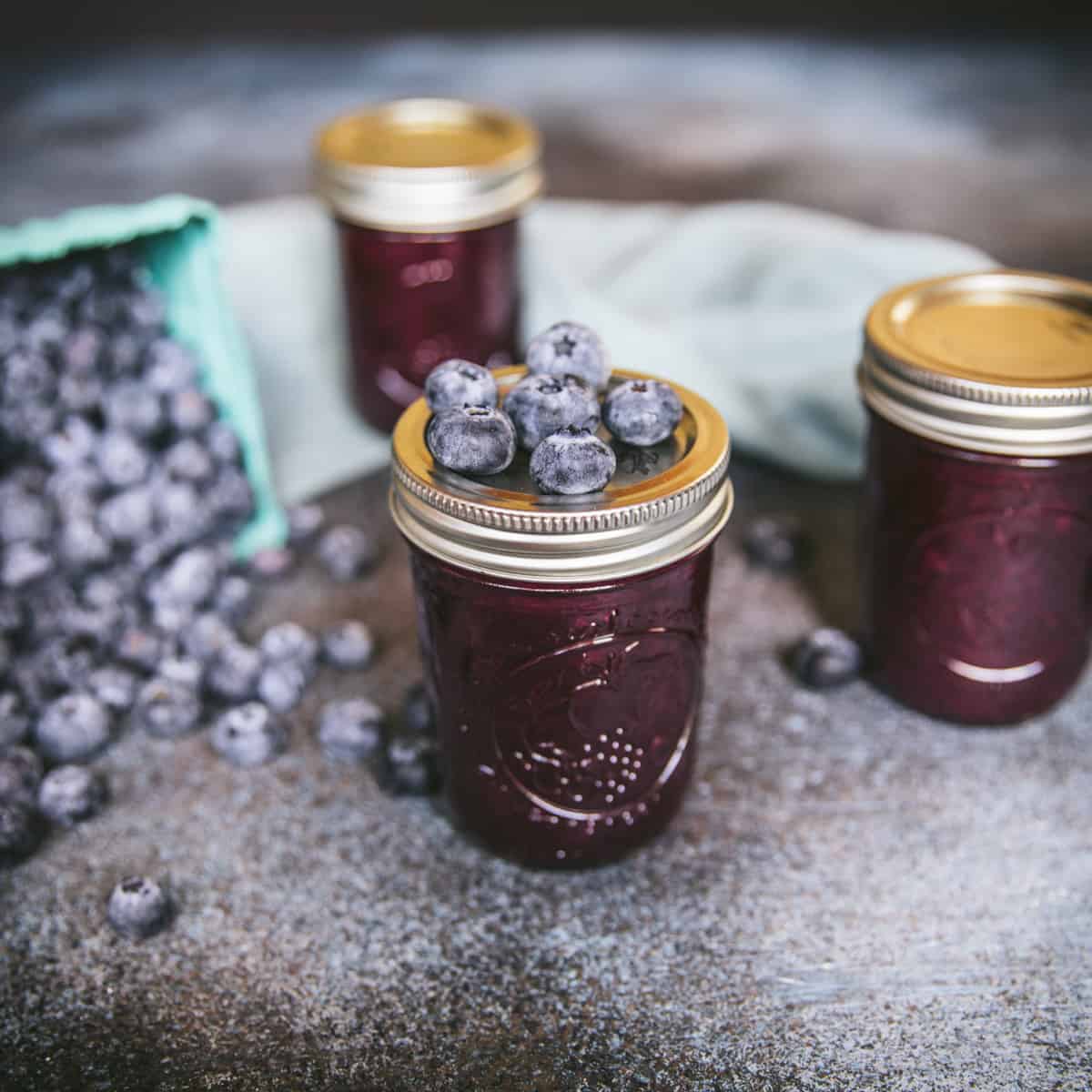 Jam in closed jars with fresh blueberries on top. 