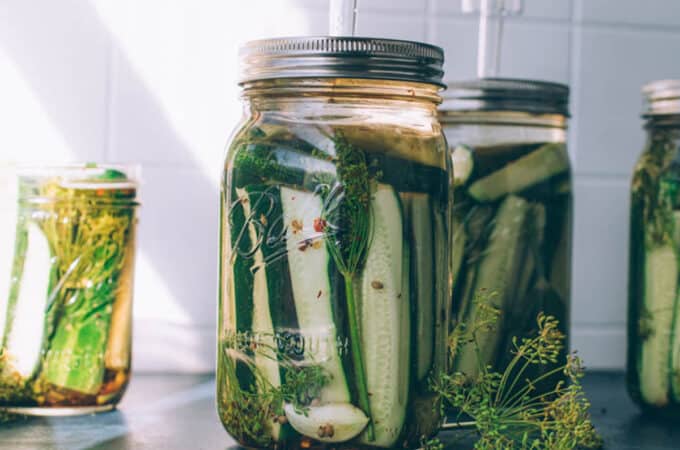Pickling cucumbers fermenting in jars with airlock lids.