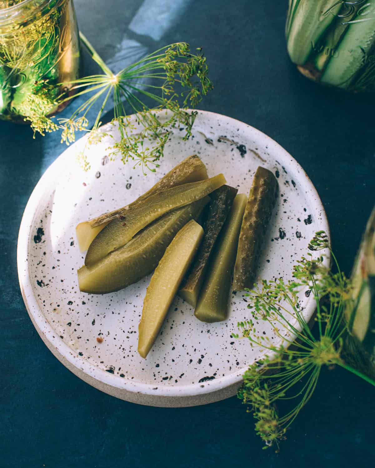 A plate with finished fermented cucumber pickles surrounded by dill flowers. 