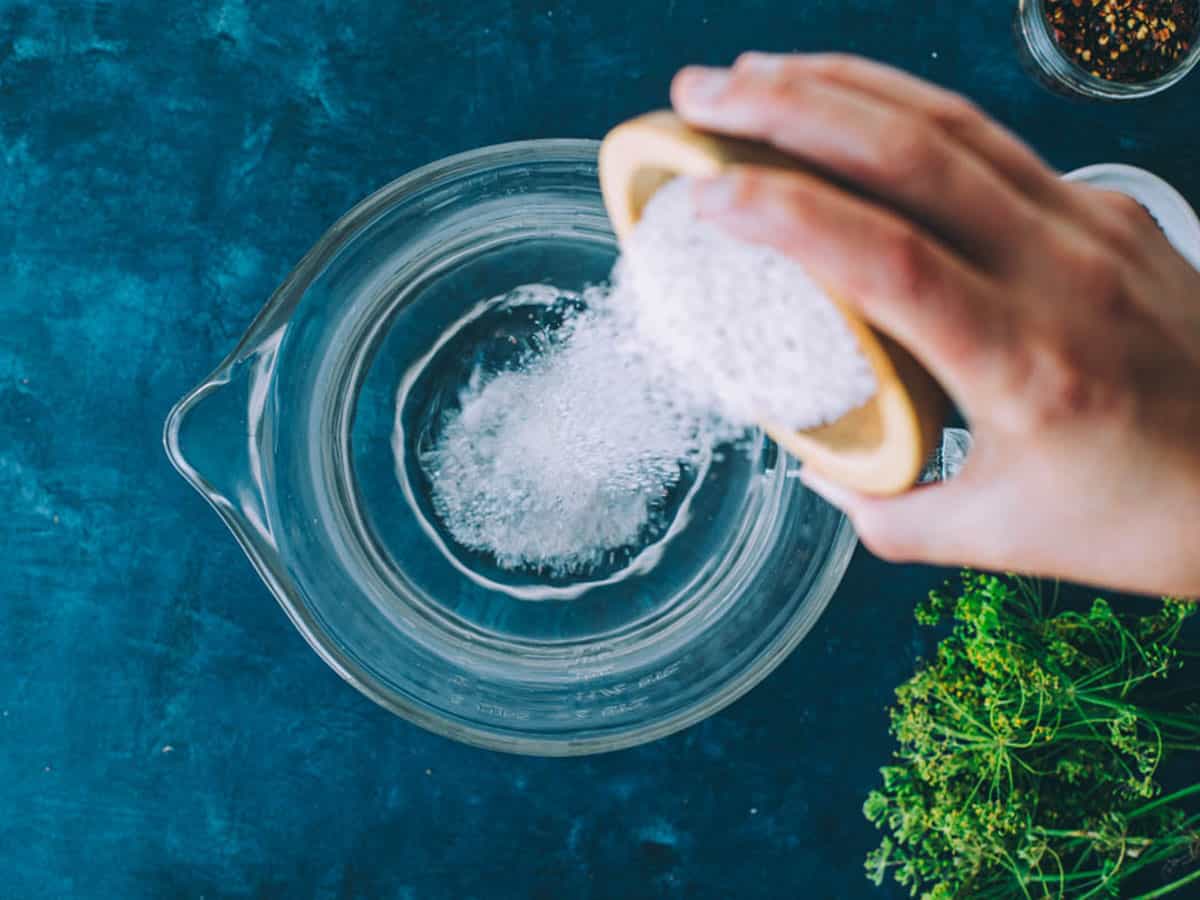 Salt pouring into a pitcher of water to make the brine. 