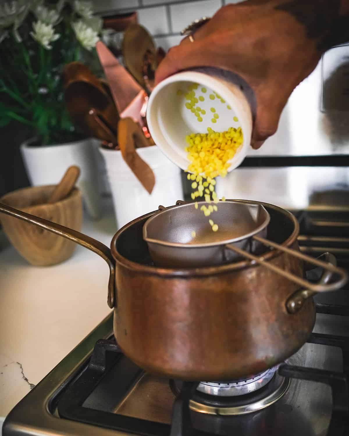 Beeswax pellets pouring into a makeshift double boiler. 