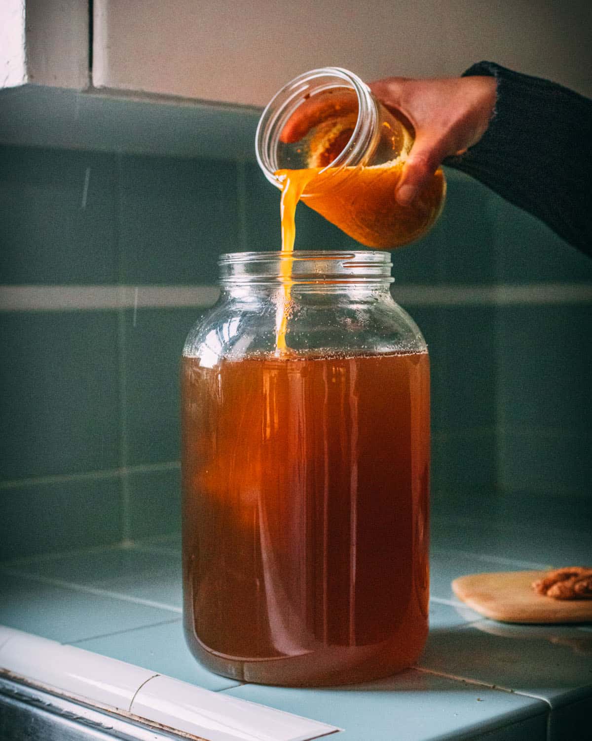 Turmeric bug being poured into a gallon glass jar to combine with the turmeric soda. 