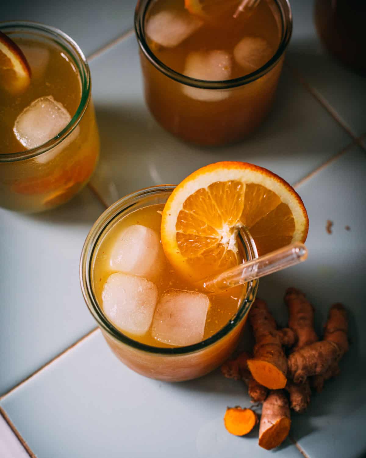A glass of turmeric soda garnished with an orange slice. 