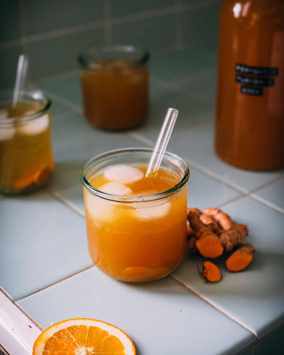 Turmeric soda in a small glass with turmeric root sitting next to it. 