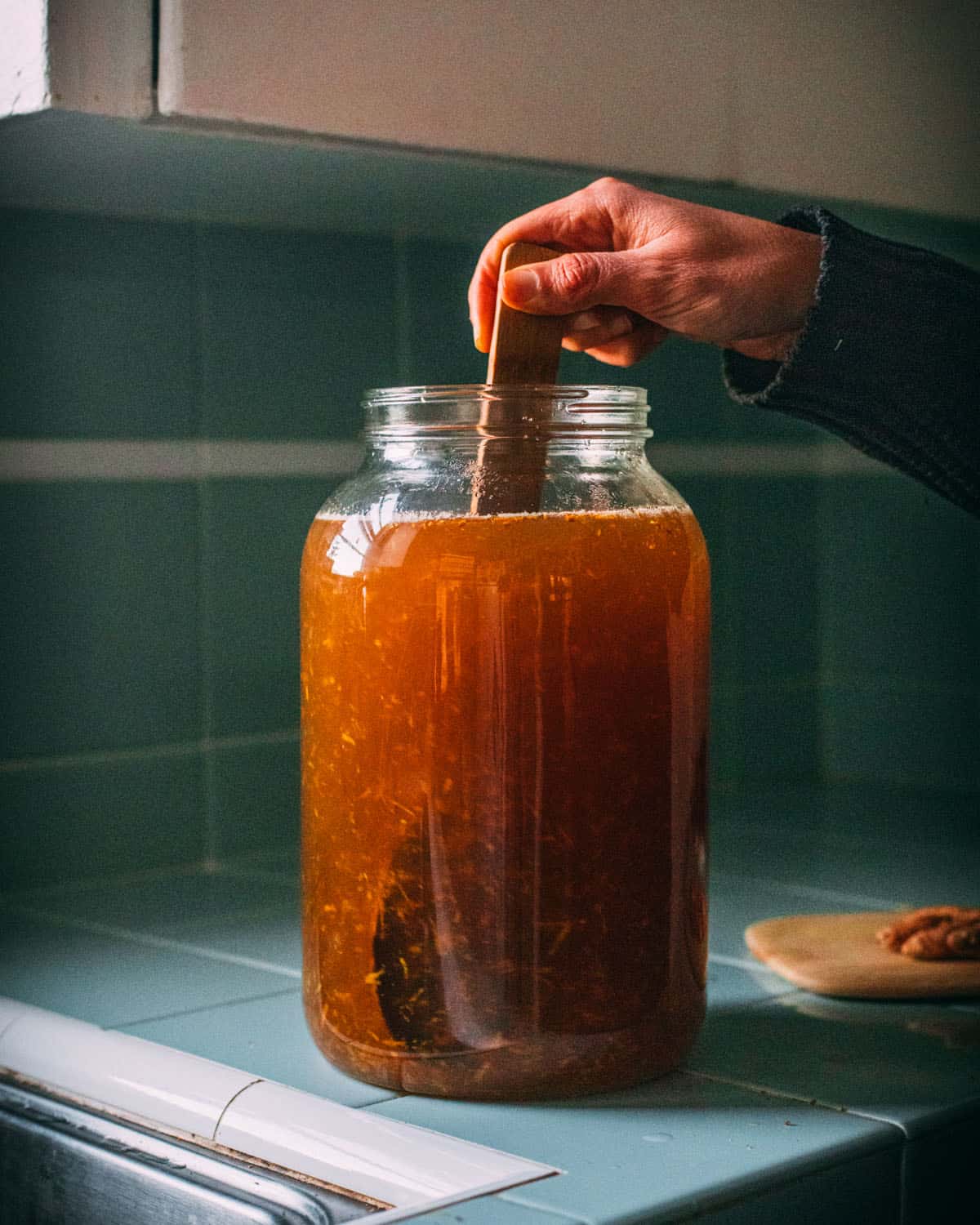 A wooden spoon stirring the turmeric bug into the jar with the soda. 