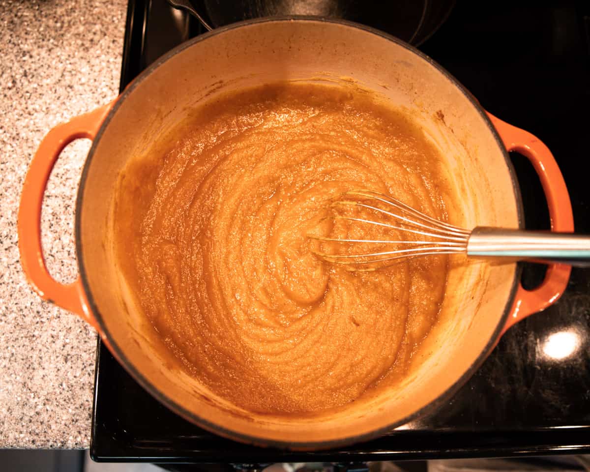 Pumpkin puree and ingredients cooking in a wide pot. 