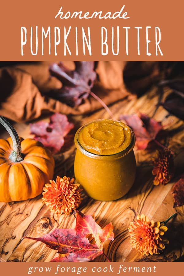 A jar of pumpkin butter surrounded by fall leaves, flowers, and a small gourd. 