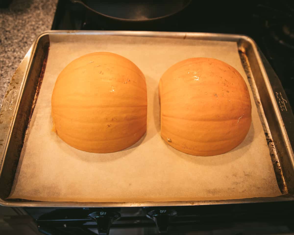 Pumpkin halves flesh side down on a roasting pan. 