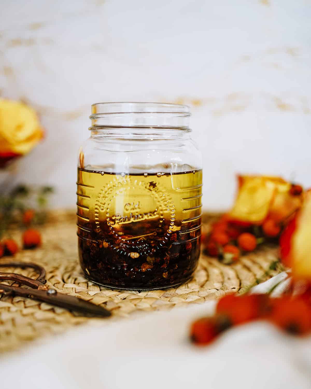 Oils in a jar mixed with dried rose hips, ready to infuse. 